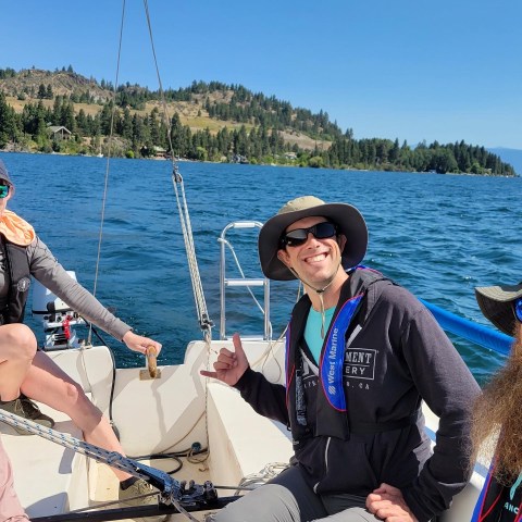 People sailing on a boat with scenic view of mountains and blue lake.