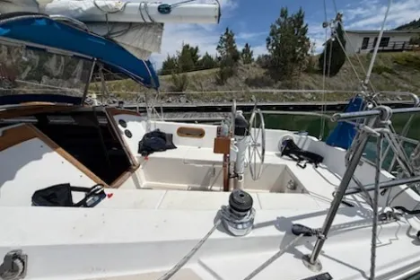 View of a sailboat's deck with seating area and visible sail rigging.